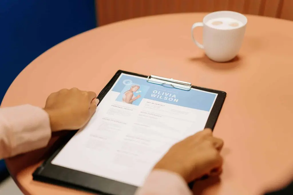 Hands holding Olivia Wilson's software engineer resume on a table with coffee