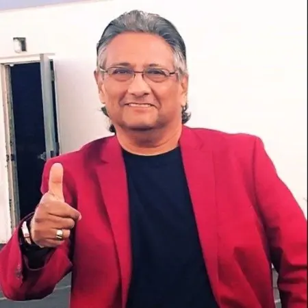 Smiling man in red blazer and glasses giving a thumbs up