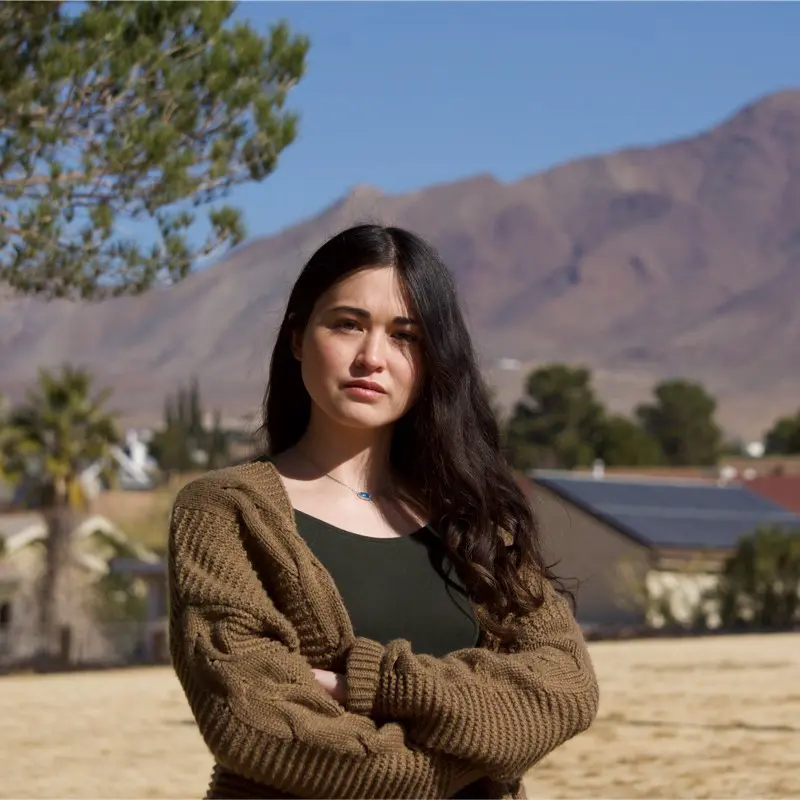Young woman in brown cable knit cardigan, desert mountains background