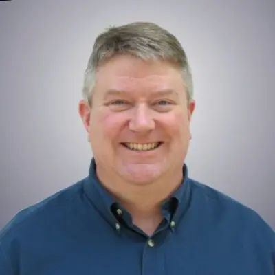 Smiling professional man blue shirt grey hair business portrait headshot