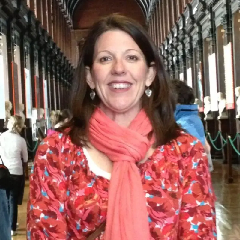 Smiling woman in a grand library hall with historical busts