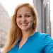 Professional headshot: smiling blonde woman in blue shirt