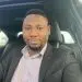 Professional Black man smiling in blazer and patterned shirt inside car