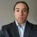 Man in business suit, light blue shirt, professional headshot for profile