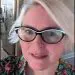 Smiling blonde woman, stylish black and white cat-eye glasses, floral shirt