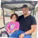 Happy man and young girl smiling while riding in golf cart