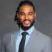 Professional Black man smiling in grey suit with dreadlocks and tie