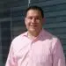 Smiling man in pink collared shirt professional headshot business profile image