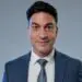 Professional businessman smiling, blue suit, white shirt, patterned tie, corporate executive headshot