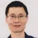 Professional headshot of Asian man wearing glasses smiling