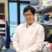 Smiling male scientist in white lab coat, glasses, in a research laboratory