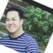 Young Asian man smiling wearing a blue striped shirt outside in nature