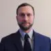 Headshot of professional business man in dark suit and patterned tie