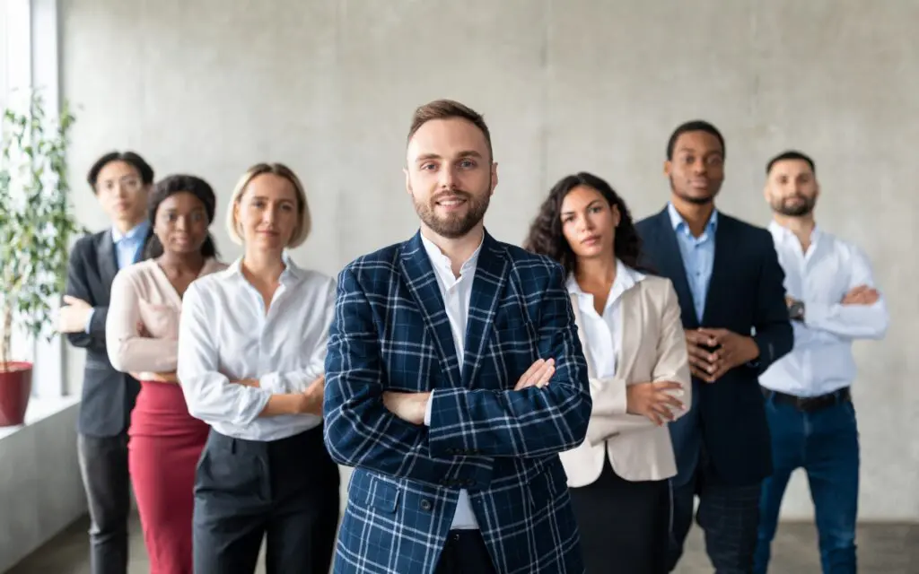 Diverse business team with smiling leader in plaid jacket, arms crossed