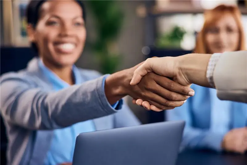Smiling business woman shakes hands, confirming agreement at a professional meeting